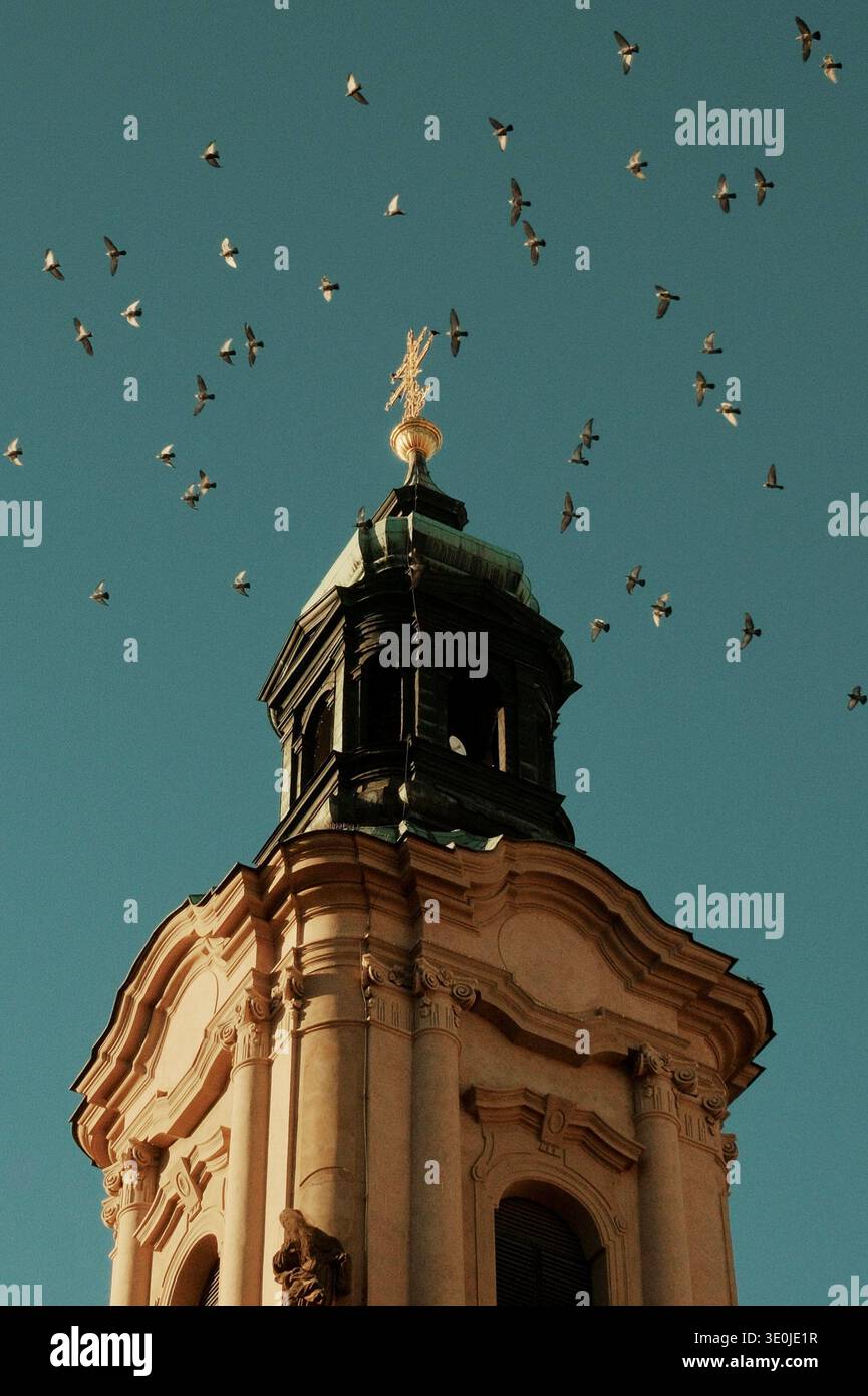 Torre della Chiesa con piccioni che volano sopra lo storico skyline di Praga, Repubblica Ceca. Foto Stock