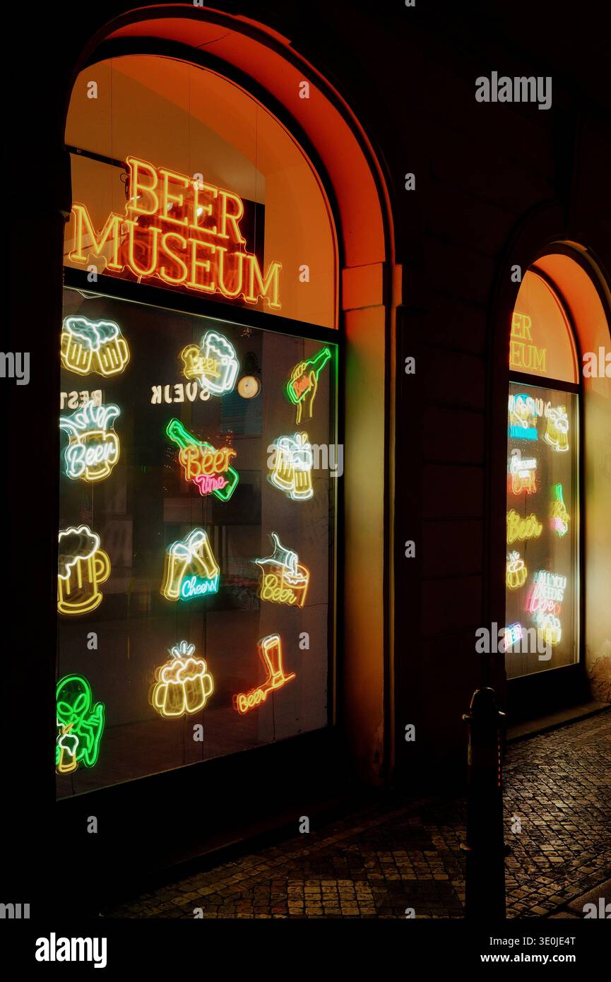 I segni al neon della finestra del museo della birra illuminano di notte nella vista esterna della chiesa di Praga, Repubblica Ceca. Foto Stock