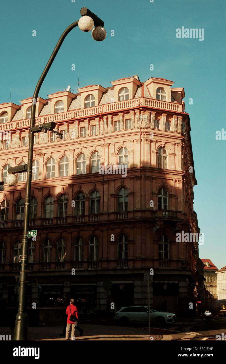 Storico edificio d'angolo rosa illuminato da una calda luce serale nel centro di Praga, Repubblica Ceca. Foto Stock