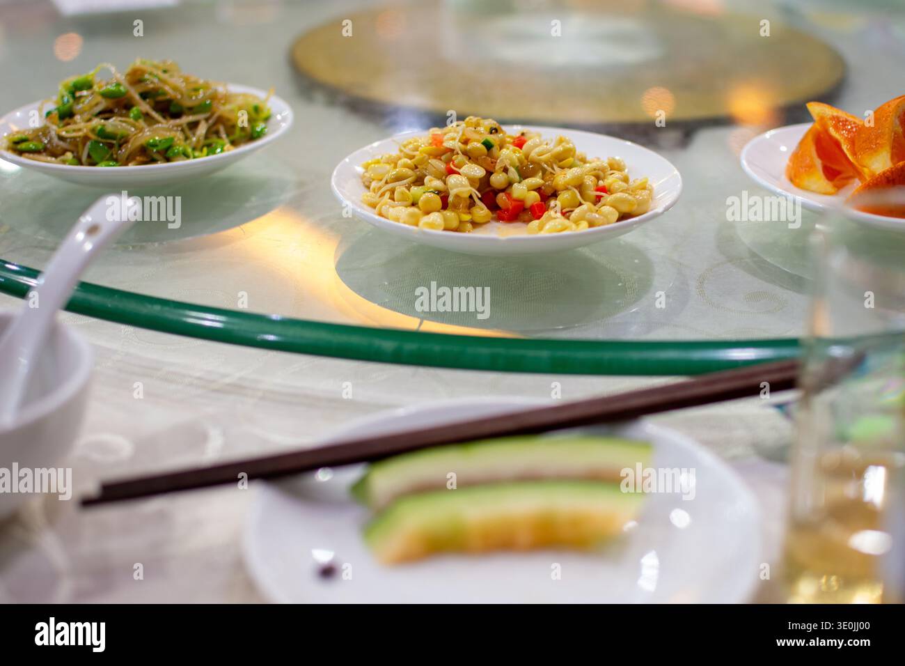 Ristorante cinese, tavolo Lazy susan con piccoli piatti di verdure saltate e piatti simili alla pasta, bacchette e bicchiere da tè, piatti atmos poco profondi Foto Stock