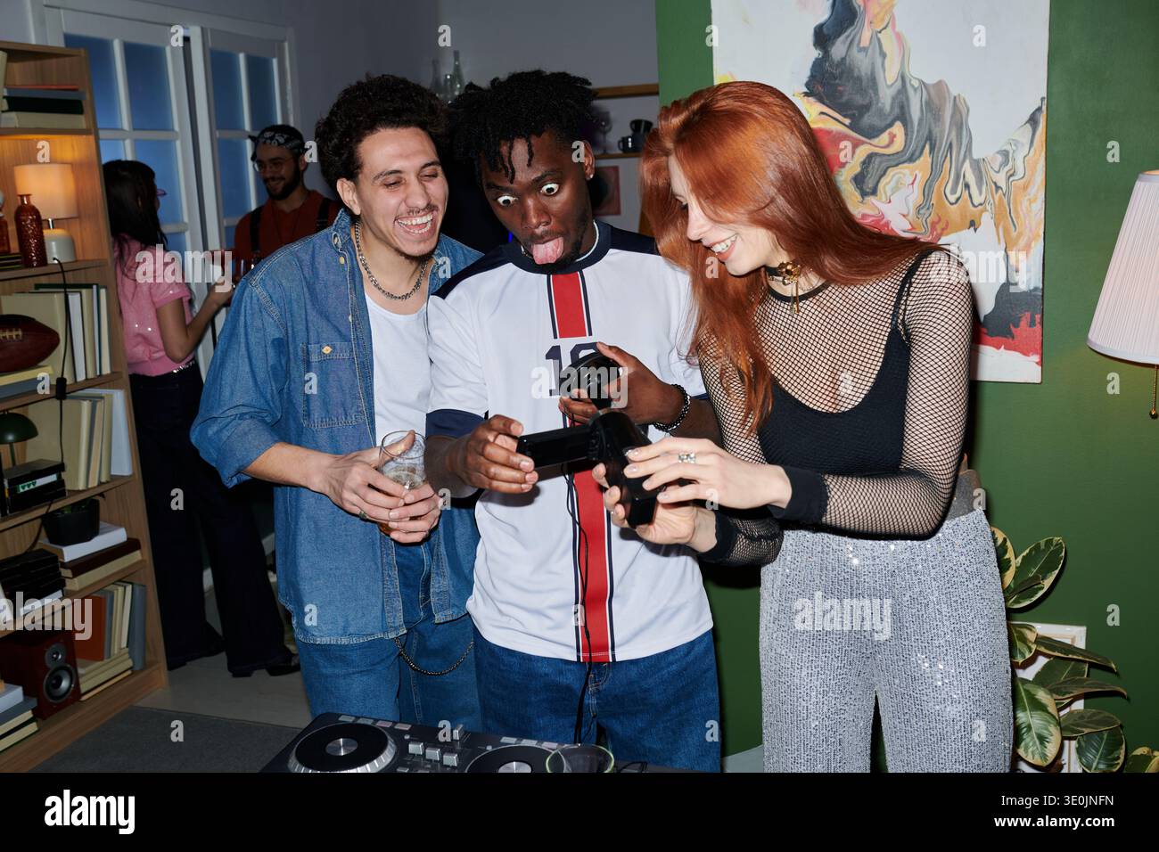 Diversi giovani che ridono e giocano al controller di videogiochi alla House Party Foto Stock