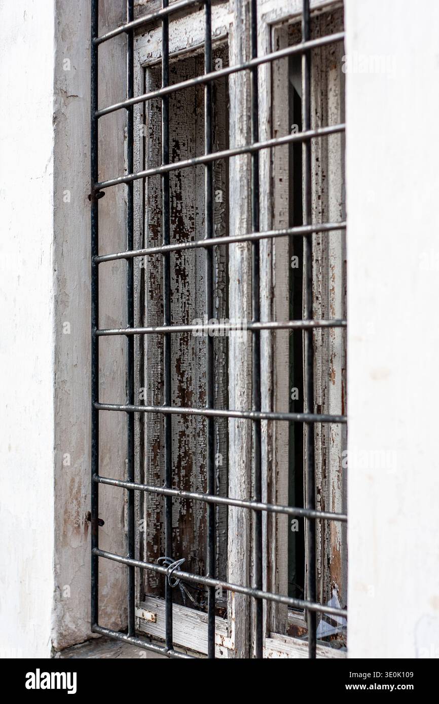 Finestra rotta con barre di ferro in un edificio abbandonato o simile a una prigione Foto Stock