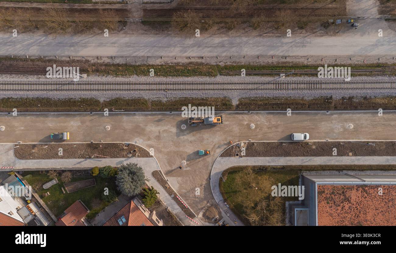Questa prospettiva aerea mostra la preparazione della superficie stradale asfaltata a siska, Lubiana, dove la ghiaia contrasta nettamente con la città circostante Foto Stock