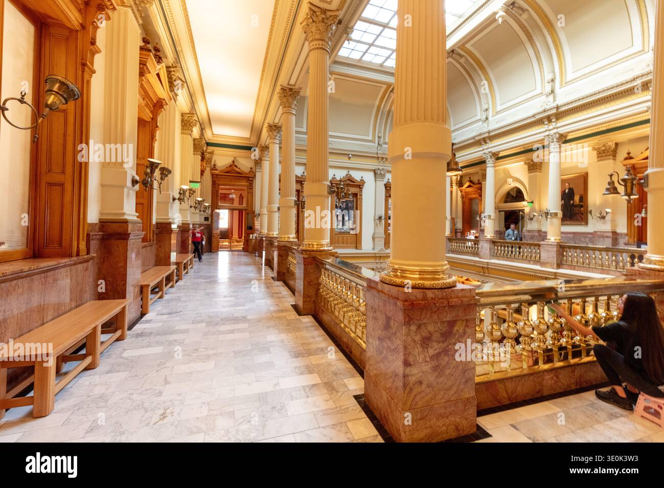 Denver, Colorado, USA - 3 marzo 2026: Una donna pulisce le ringhiere di ottone lungo una scala all'interno dello storico edificio del Campidoglio dello stato del Colorado a Denv Foto Stock