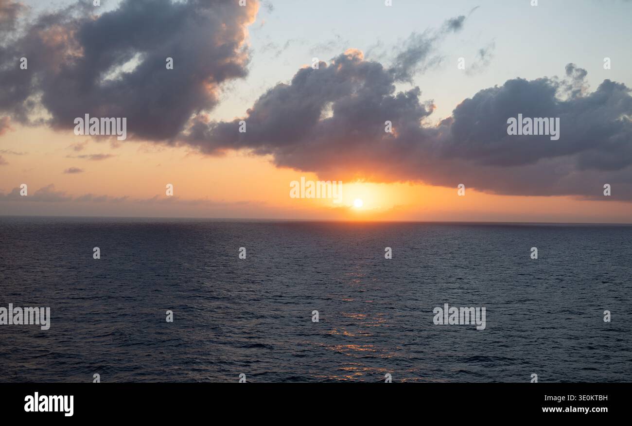 Tramonto dorato sul Mar dei Caraibi con spettacolari nuvole e luce solare che si riflette sull'orizzonte dell'oceano. Foto Stock