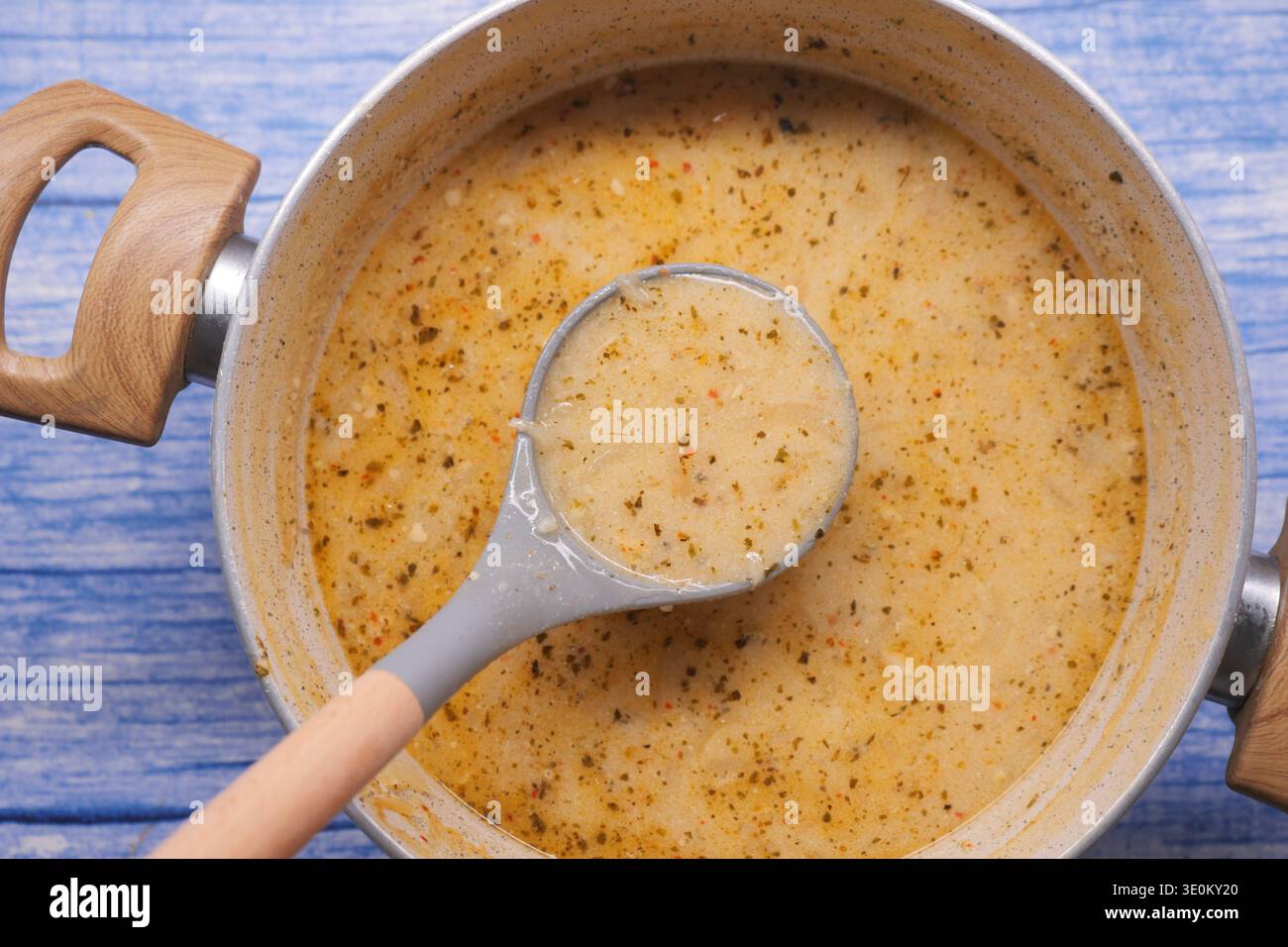 Cuocere la zuppa in una pentola su un bancone della cucina vicino al legno blu Foto Stock
