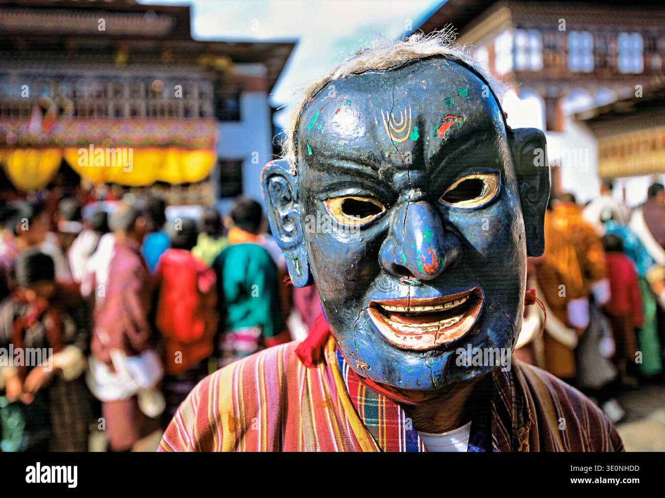 Il partecipante al festival indossa una maschera blu tradizionale e capelli bianchi durante il festival di danza Cham in Bhutan. La gente si riunisce per celebrare l'evento. Foto Stock