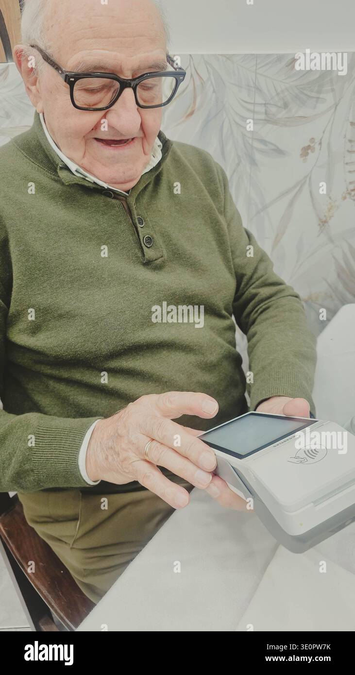 L'uomo anziano impara e utilizza un terminale di pagamento per una transazione moderna Foto Stock