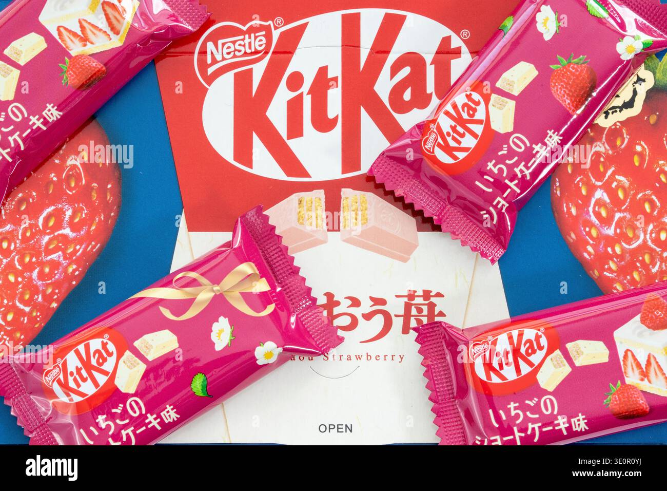 Copertina con foto della scatola di Kitkat al gusto di Cheesecake alla fragola giapponese e quattro mini bar kitkat avvolti sparsi sulla parte superiore. Foto Stock