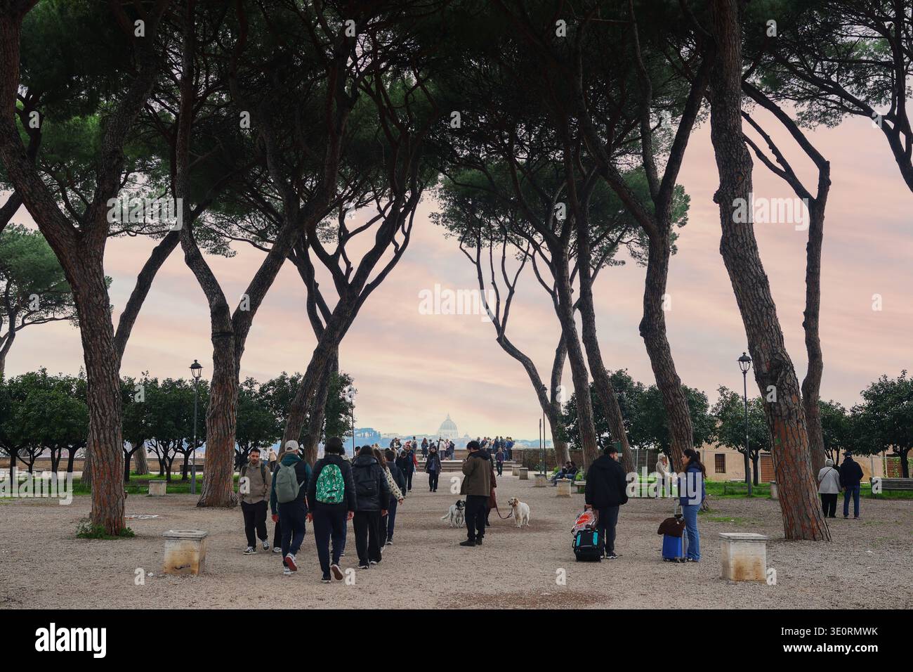 Roma, Italia - 2 marzo 2026: Persone che camminano attraverso il vicolo dei pini sul punto panoramico del colle Pinciano con vista verso la Basilica di San Pietro. Foto Stock