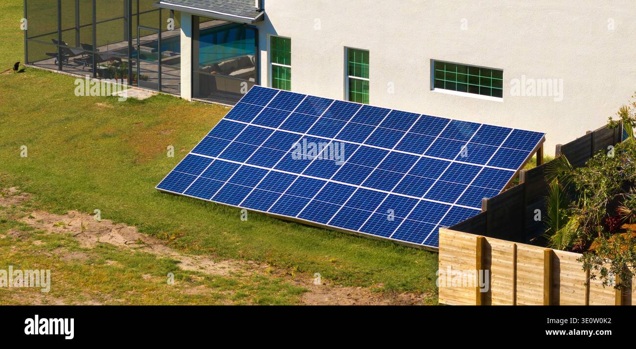Casa autonoma con pannelli fotovoltaici solari montati su un telaio indipendente sul terreno del cortile per la generazione di energia elettrica ecologica pulita Foto Stock