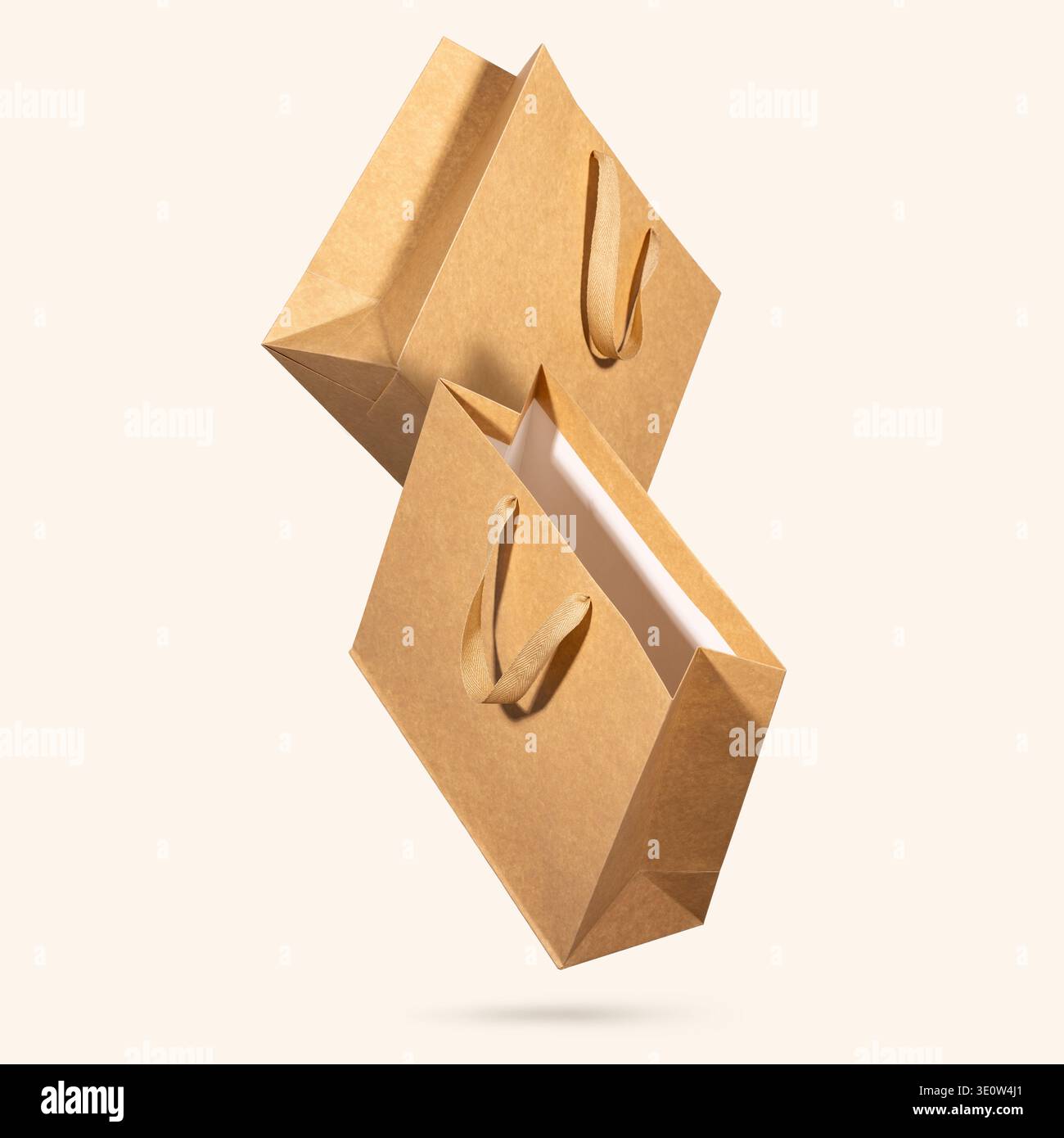 Due sacchetti per la spesa in carta kraft con manici in tessuto che galleggiano su sfondo beige chiaro. Concetto di tendenze di packaging sostenibili, vendita al dettaglio eco-consapevole Foto Stock