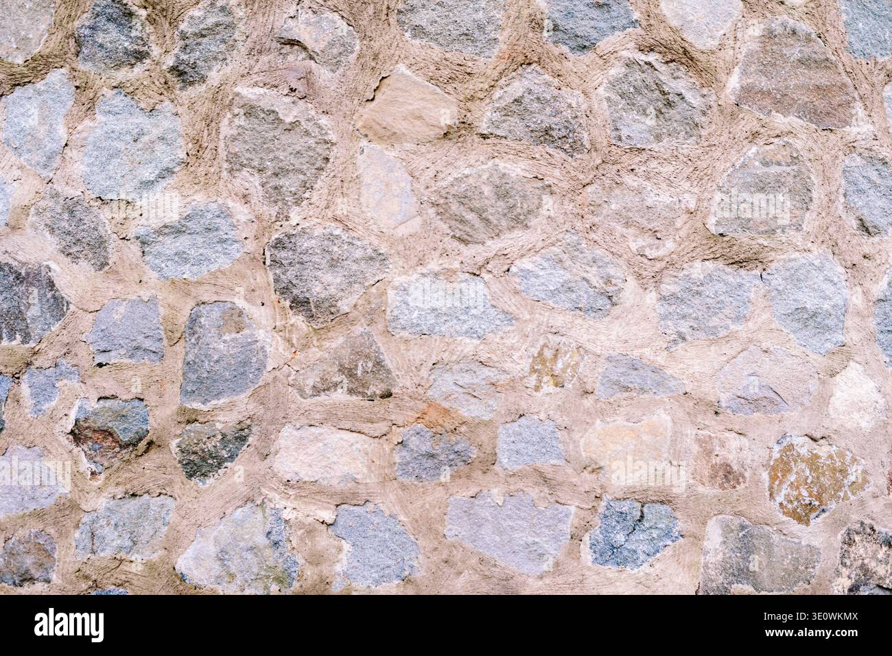 Questa immagine presenta un muro di pietra naturale che mette in risalto i vari colori e la consistenza ruvida delle rocce, in robusto Malta, perfetto come un bac resistente Foto Stock