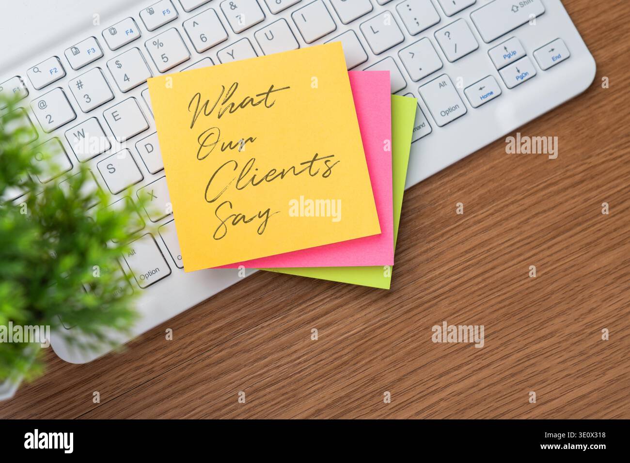 Vista dall'alto verso il basso della tastiera di un computer e una pila di colori adesivi con testo che dicono i nostri clienti. Feedback dei clienti, testimonianze e recensioni online Foto Stock