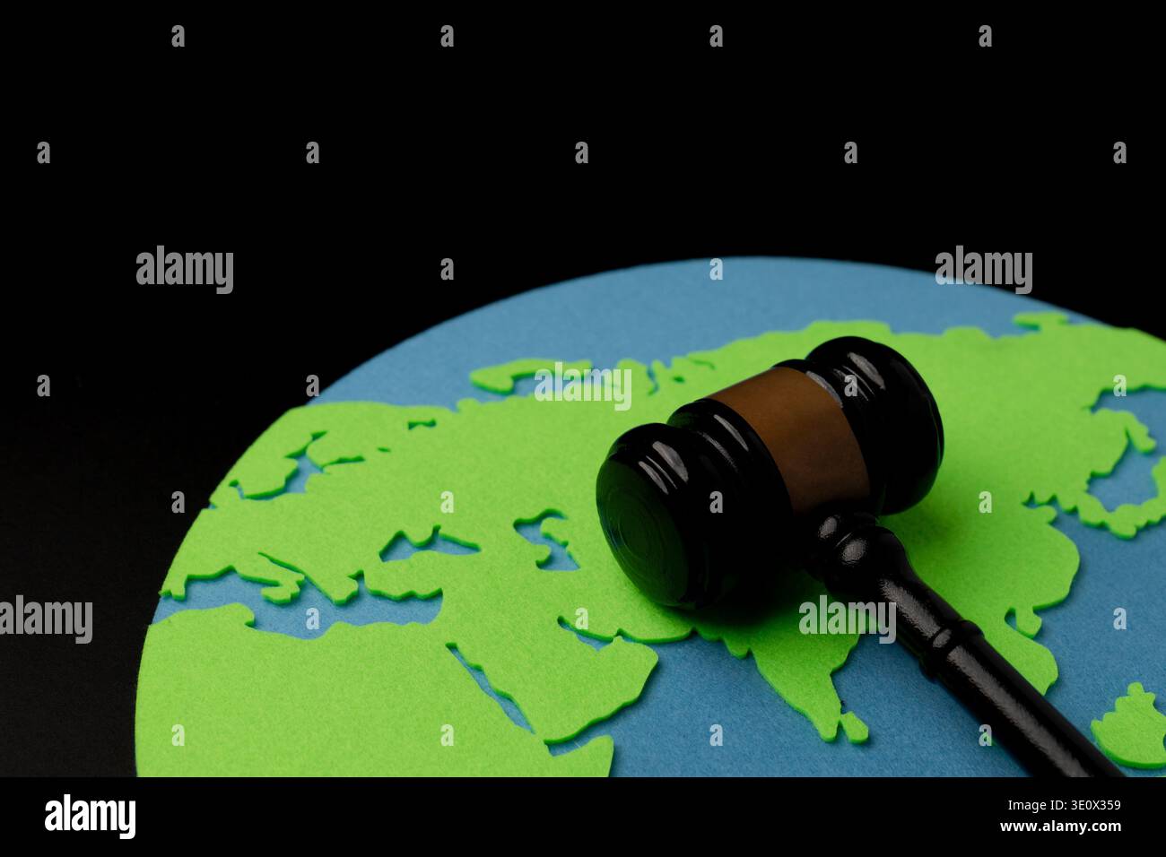 Il martelletto di un giudice su una mappa del mondo ritagliata su uno sfondo scuro. Diritto internazionale, giustizia globale, normative ambientali e diritti umani conce Foto Stock