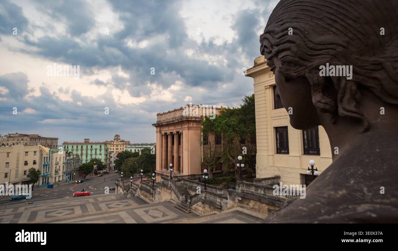 Statua in bronzo di Alma Mater che si affaccia sul paesaggio urbano dell'Avana con auto d'epoca e un cielo tempestoso, l'Università dell'Avana, Cuba Foto Stock