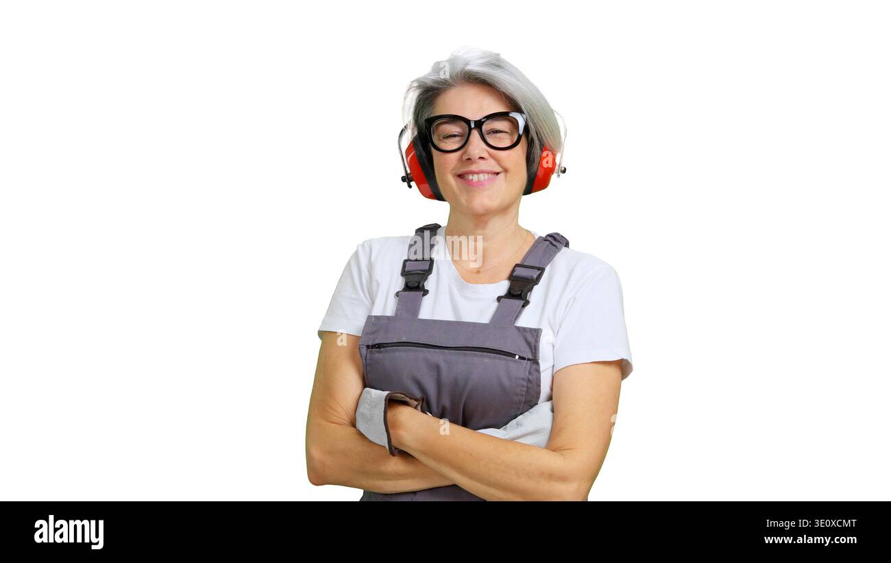 Donna sorridente che indossa tute da lavoro e cuffie di sicurezza Foto Stock
