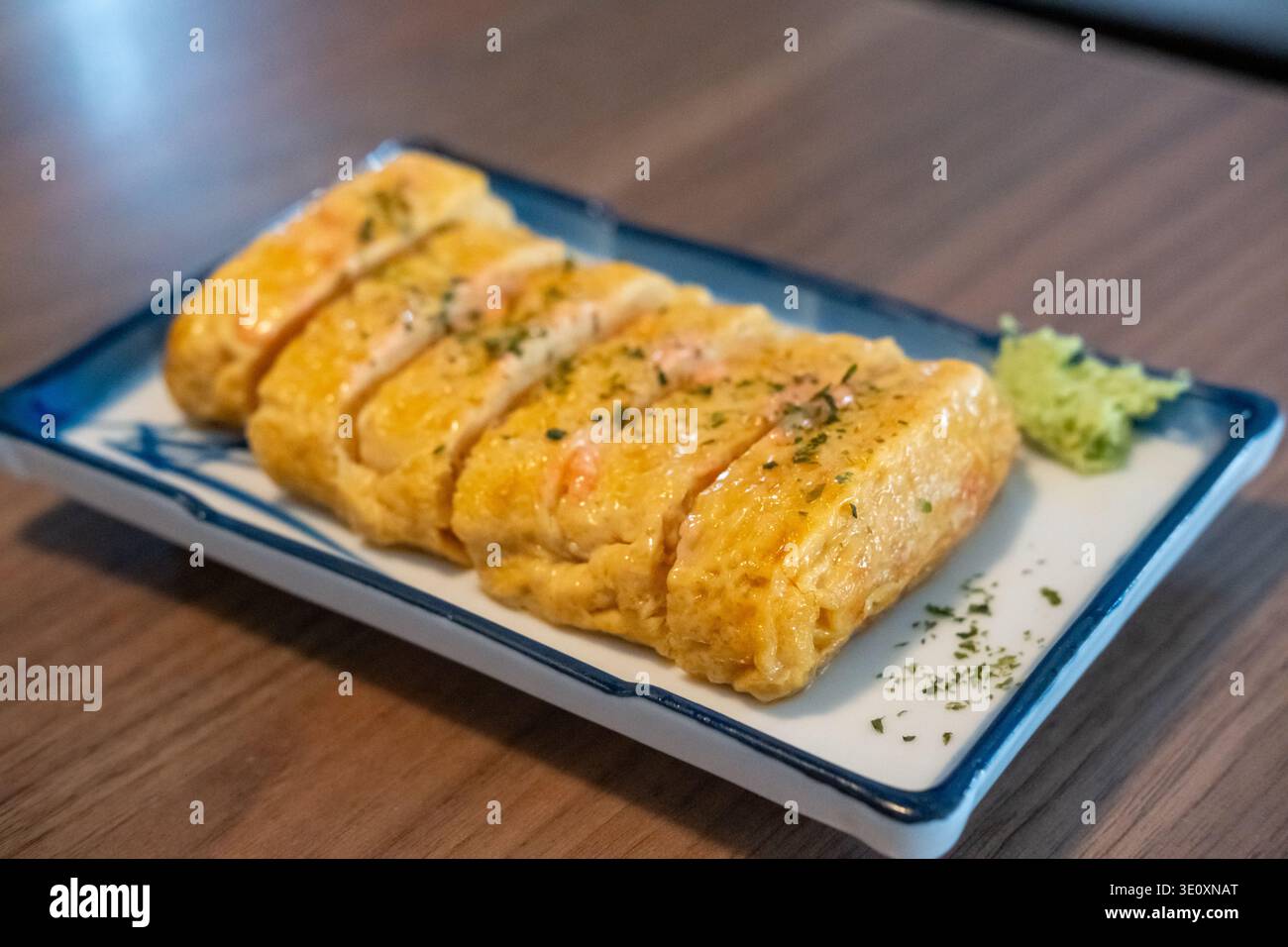 Tamagoyaki, un'omelette giapponese preparata arrotolando diversi strati di uova sbattute fritte, servita su un piatto. Foto Stock