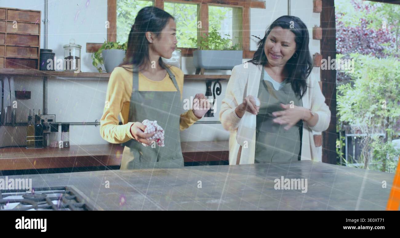 Due donne parlanti che indossano grembiuli grigi dietro la grande isola della cucina, tenendo in mano un asciugamano Foto Stock