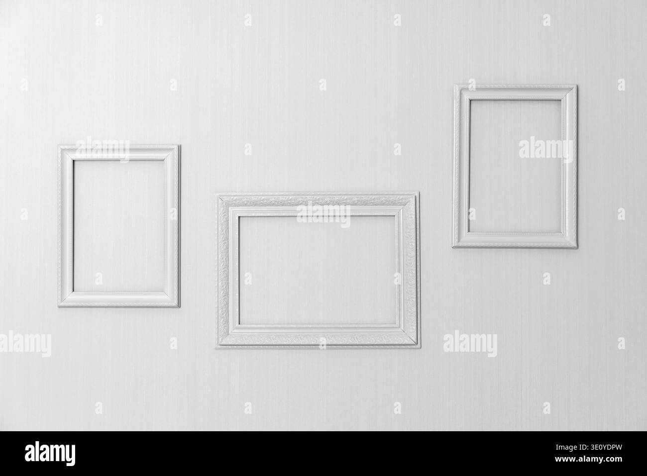 Disposizione minimale di tre cornici bianche vuote montate su una parete testurizzata, perfette come mockup di gallerie, arredamento di interni o sfondo Foto Stock