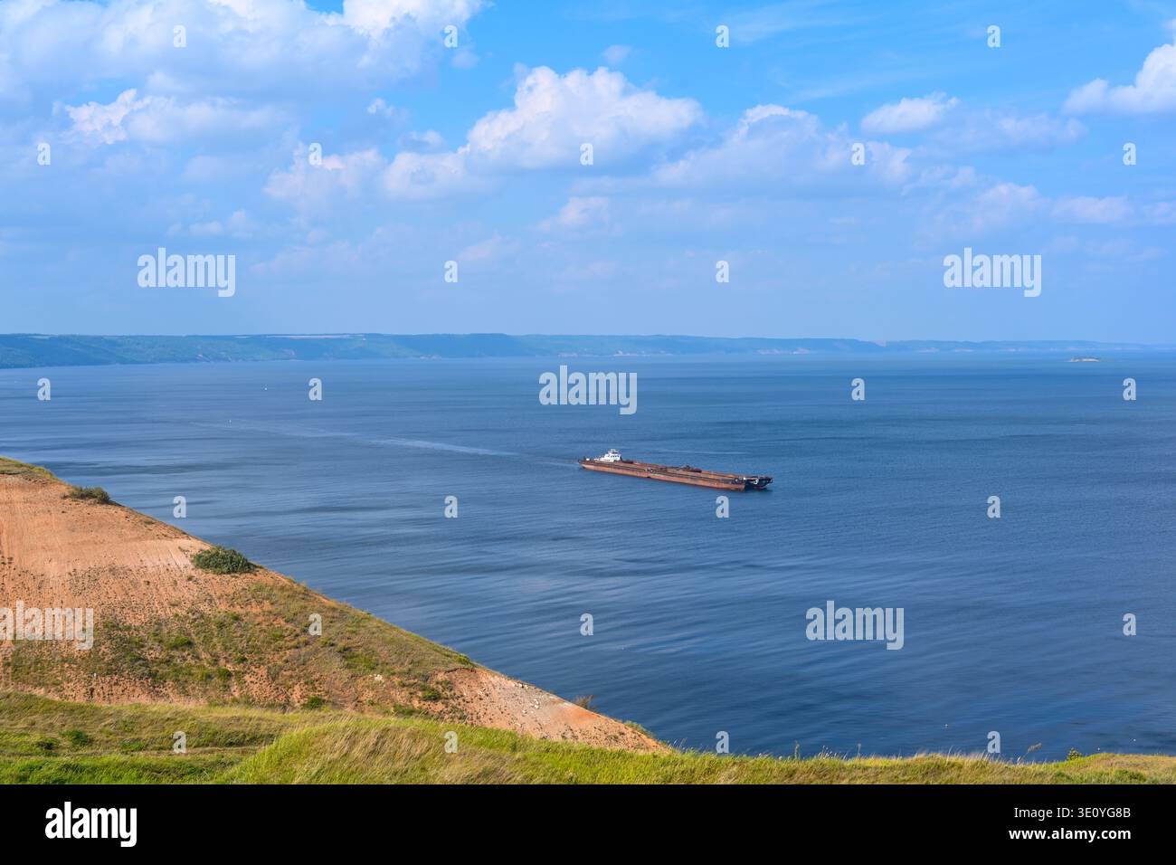 Un rimorchiatore articolato e una nave portarinfuse trasportano sabbia e materiali da costruzione sul fiume. La grande chiatta naviga lungo l'ampia rive del Volga Foto Stock
