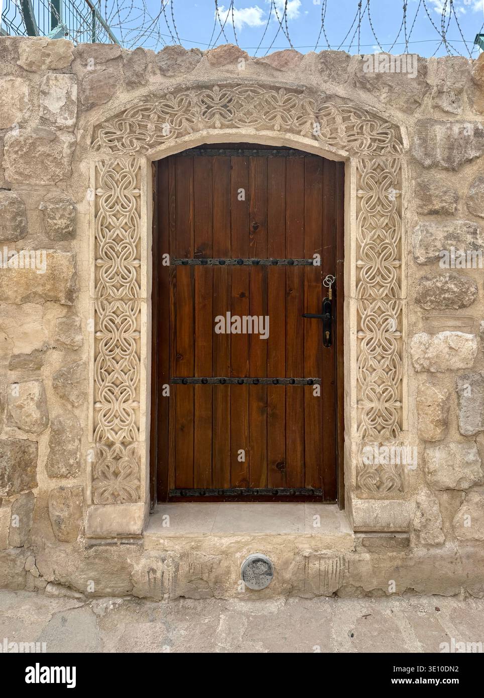 Porta d'ingresso della tradizionale casa di pietra mediorientale. Porta in legno battuto in ferro su una strada della città mediorientale. Strade di Mardin, Turchia Foto Stock
