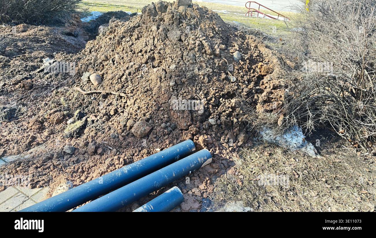 Sito di scavo con tubi di pubblica utilità in plastica e pali di terreno per l'installazione di condotte sotterranee Foto Stock