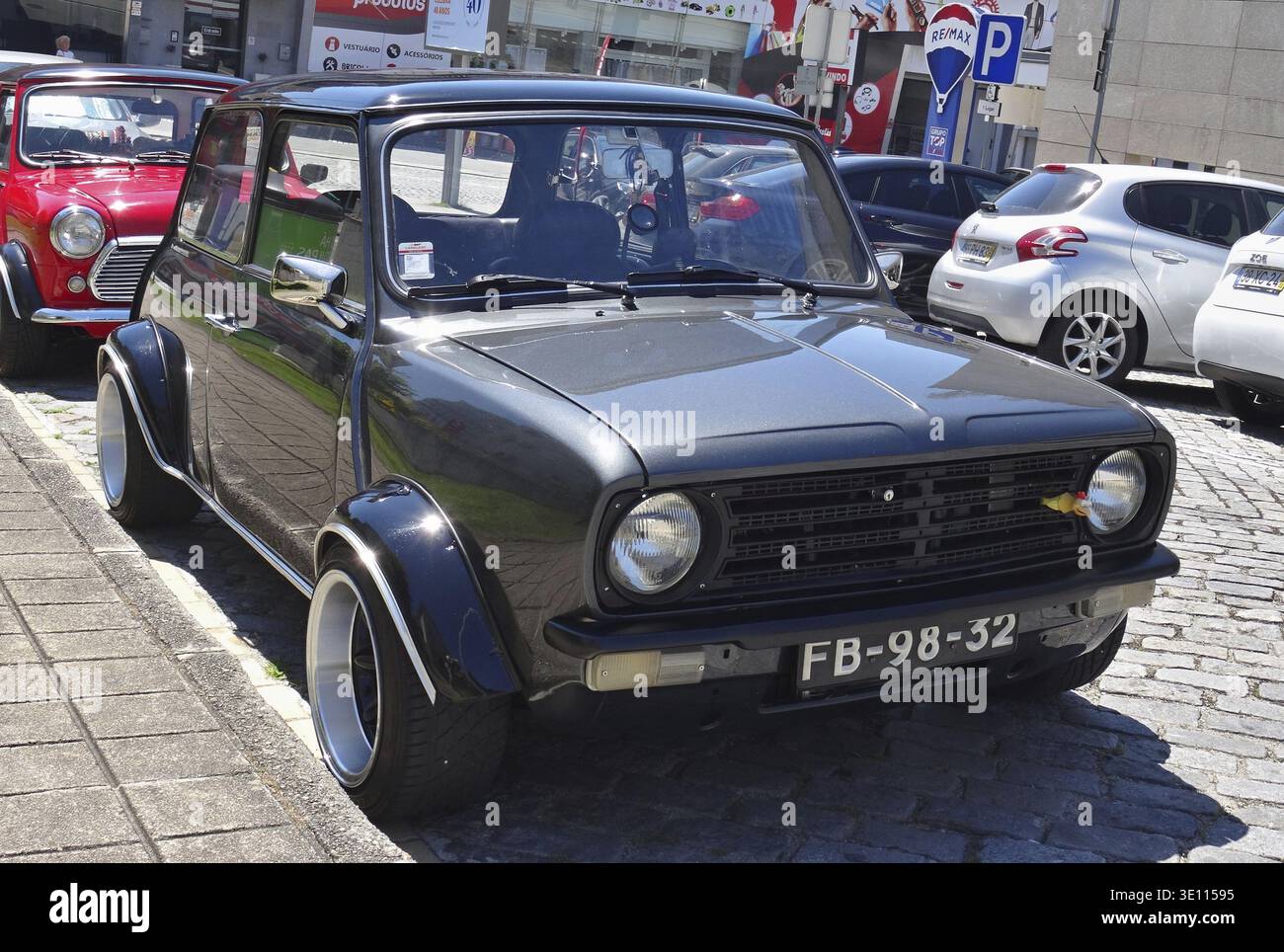 Mini Cooper sintonizzata con ampi passaruota e cerchi in lega parcheggiati vicino a una mini Cooper rossa Foto Stock
