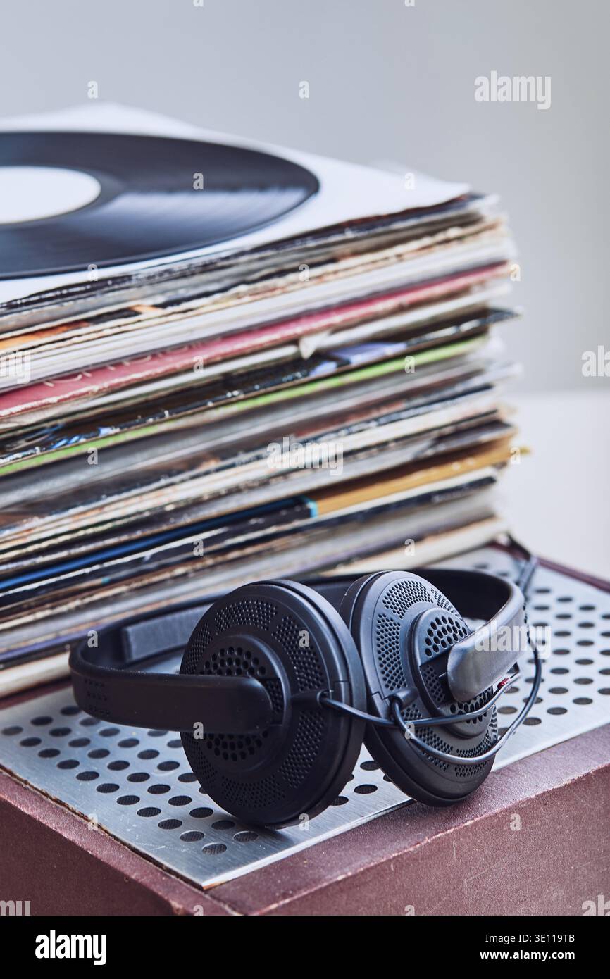 Stack di molti dischi in vinile nero, cuffie messe in cima al vinile. Spazio di copia per il testo. Persone since, momenti reali, situazioni autentiche Foto Stock