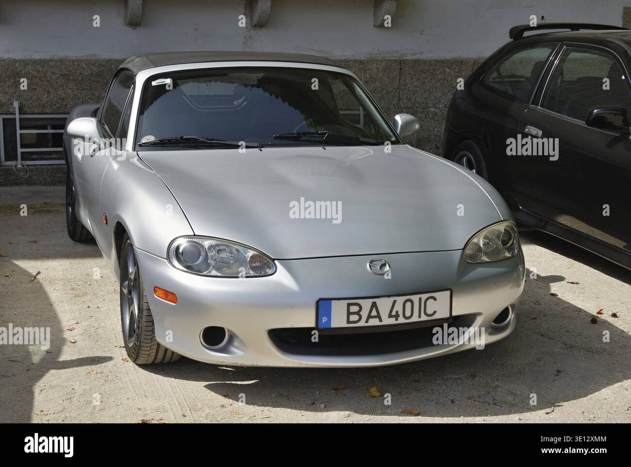 Vista frontale di una Mazda MX-5 Miata argentata parcheggiata vicino a un edificio, che mostra il suo design elegante Foto Stock