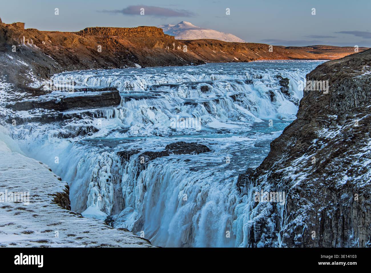 Cascata di Gullfoss in inverno con formazioni di ghiaccio e il monte Bláfell sullo sfondo, Islanda. Le cascate parzialmente congelate del fiume Hvitá si inseriscono in un profondo canyon. Foto Stock