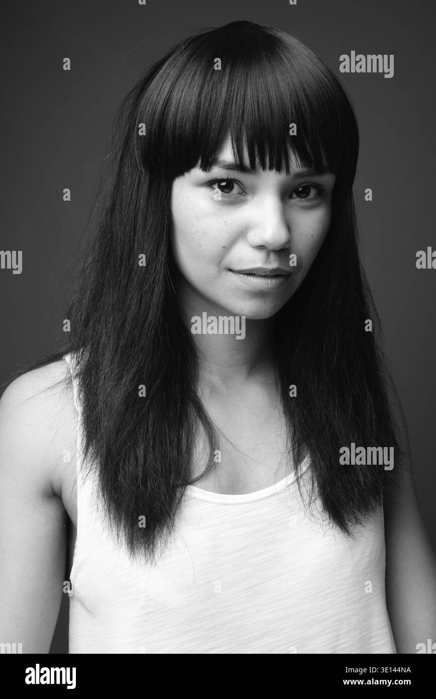 Studio shot della giovane donna asiatica contro uno sfondo grigio in bianco e nero Foto Stock