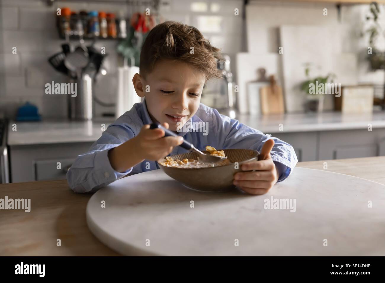 Bambino sorridente che mangia cereali preparati al momento con latte Foto Stock