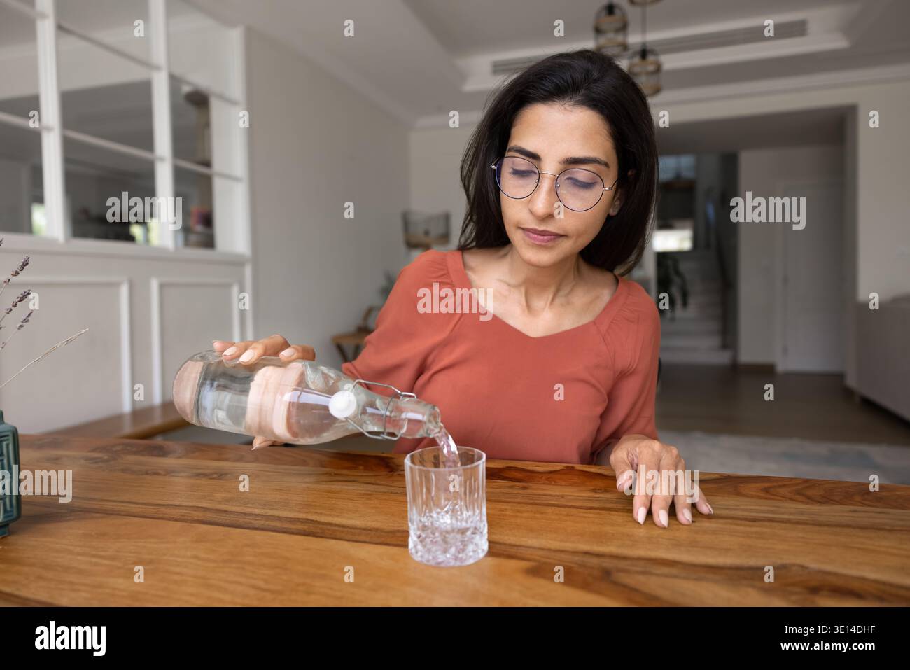 Giovane donna degli anni '30 che versa acqua nel vetro Foto Stock