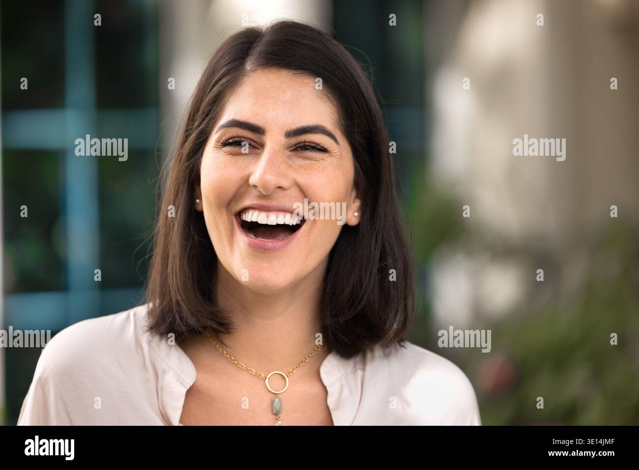 Allegra giovane bella donna ispanica che posa all'aperto per un ritratto Foto Stock