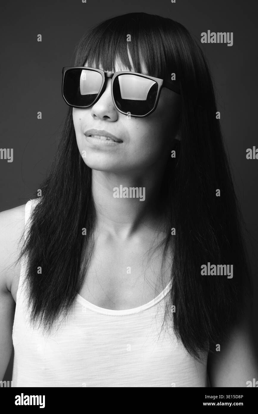 Studio shot della giovane donna asiatica contro uno sfondo grigio in bianco e nero Foto Stock