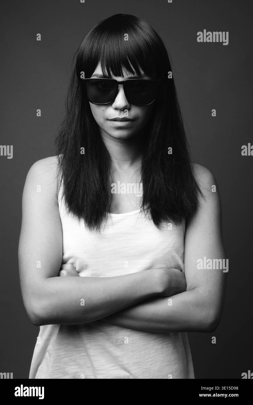 Studio shot della giovane donna asiatica contro uno sfondo grigio in bianco e nero Foto Stock