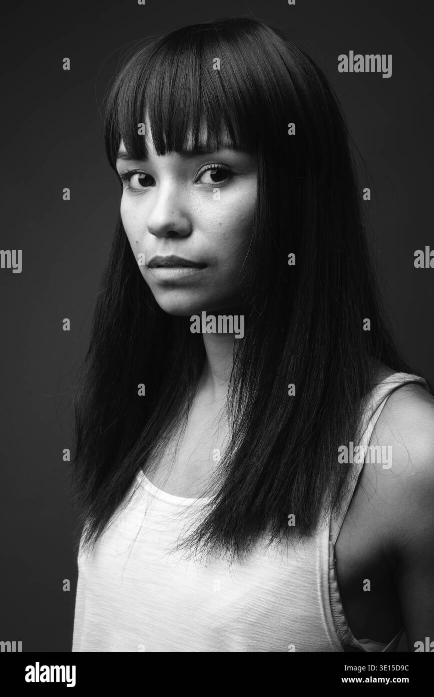 Studio shot della giovane donna asiatica contro uno sfondo grigio in bianco e nero Foto Stock