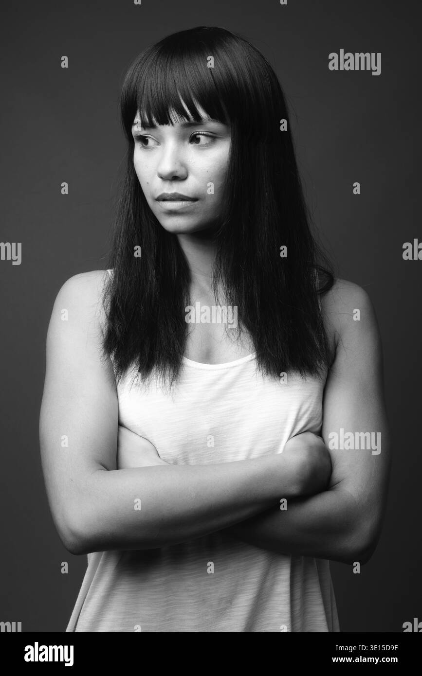 Studio shot della giovane donna asiatica contro uno sfondo grigio in bianco e nero Foto Stock