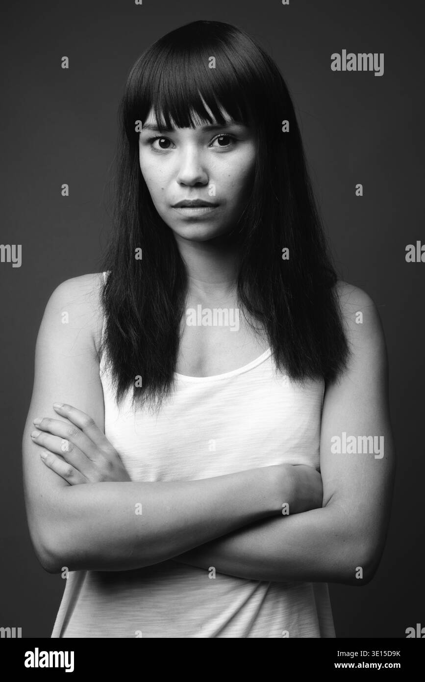 Studio shot della giovane donna asiatica contro uno sfondo grigio in bianco e nero Foto Stock