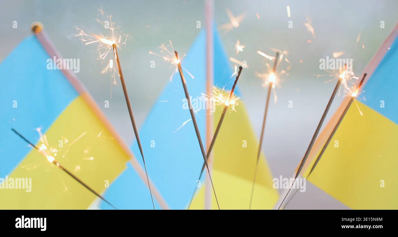 Festeggiamenti con bandiere e scintillanti ucraini durante un evento festivo in uno spazio pubblico al tramonto Foto Stock