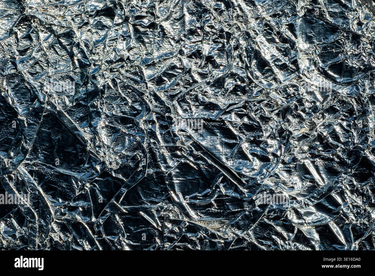 Superficie lucida e ondulata in lamina di alluminio che crea uno sfondo metallico a trama astratta Foto Stock
