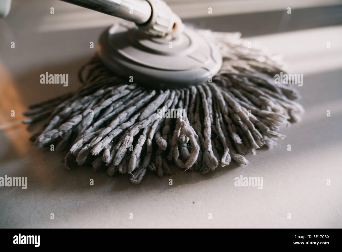 Primo piano della testina in microfibra grigia sul pavimento piastrellato, dettaglio dell'utensile per la pulizia degli interni Foto Stock