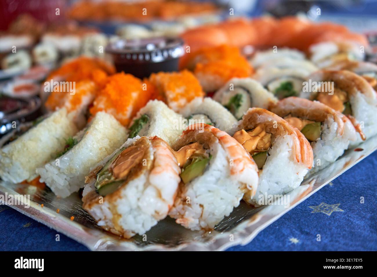 Una foto ravvicinata di un elaborato piatto di sushi con vari tipi di panini giapponesi disposti su un piatto rettangolare. Nella Foto Stock