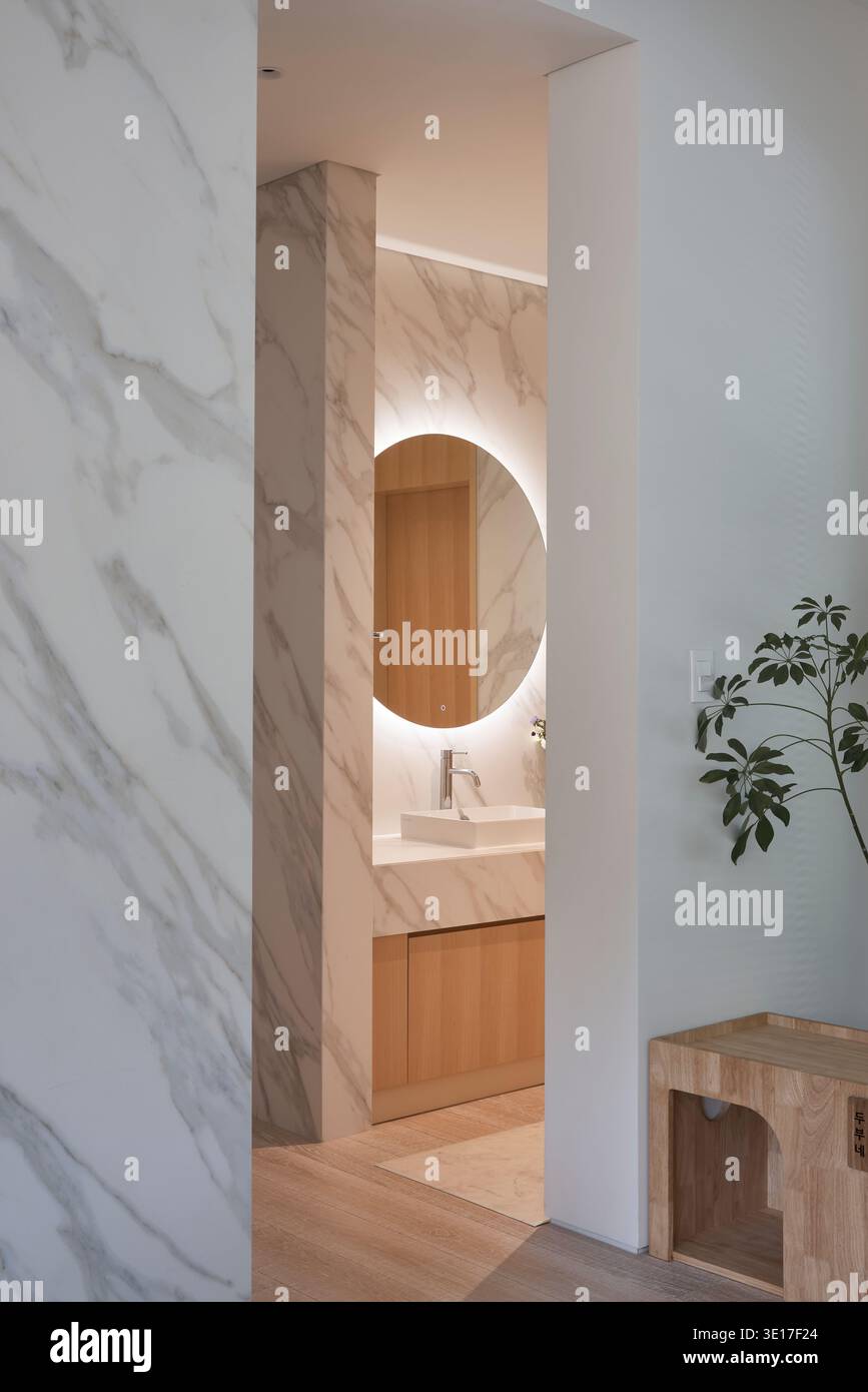 Bagno rivestito in marmo con specchio arrotondato. Foto Stock
