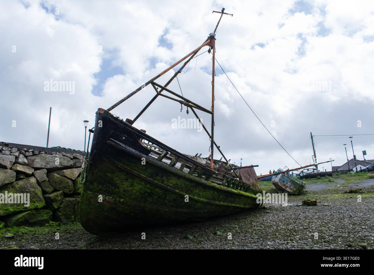 Vecchia barca arrugginita che tocca il pavimento a causa della bassa marea in un porto dell'Irlanda del Nord Foto Stock