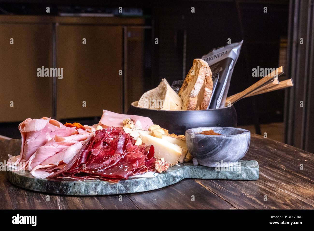 Un delizioso tagliere di salumi con un assortimento di prosciutto stagionato e affettati sottili. Presentato su un tavolo rustico, perfetto per piatti gourmet Foto Stock