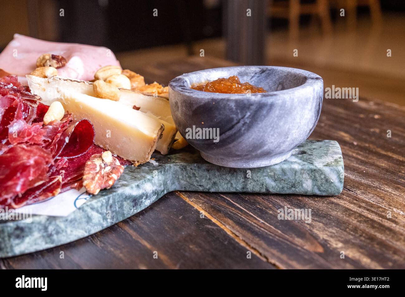 Un delizioso tagliere di salumi con prosciutto stagionato, formaggi assortiti e noci miste. La tavola è disposta ad arte, perfetta per uno stile gastronomico Foto Stock