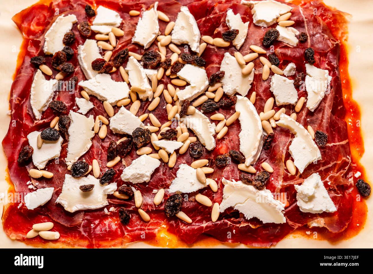 Una deliziosa torta gourmet con strati di salumi, formaggio morbido, uvetta e pinoli pronti per essere cucinati. I colori vivaci evidenziano l'ingr Foto Stock