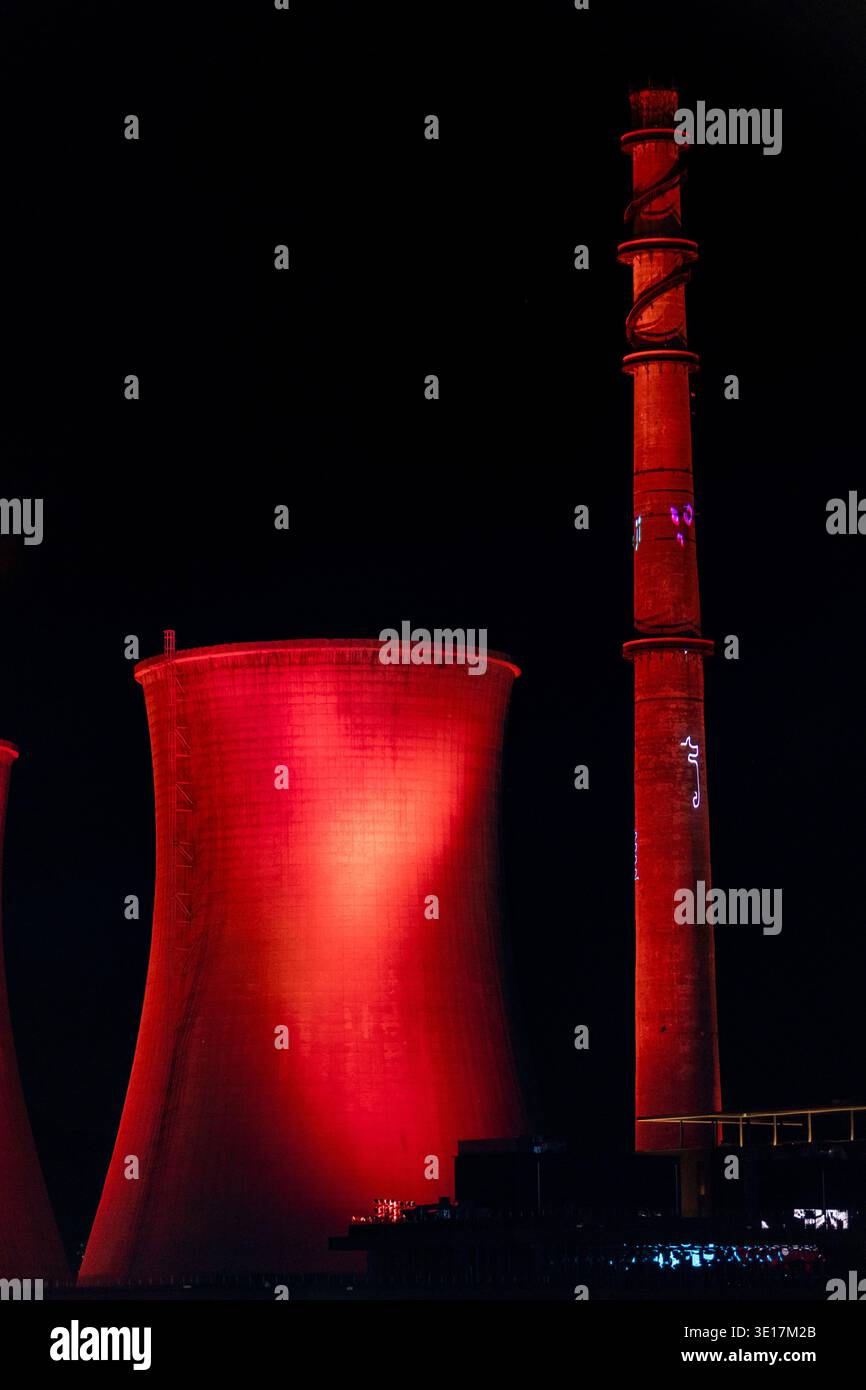 L'immagine mostra una centrale elettrica industriale illuminata contro il cielo notturno di Pechino. Le strutture luminose creano un contrasto visivo sorprendente, Foto Stock